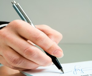 Photo of ballpoint in the female hand over a contract